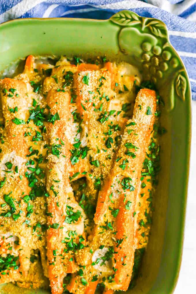 Roasted carrots in a creamy sauce with toasted breadcrumbs on top and chopped parsley sprinkled over the baking dish