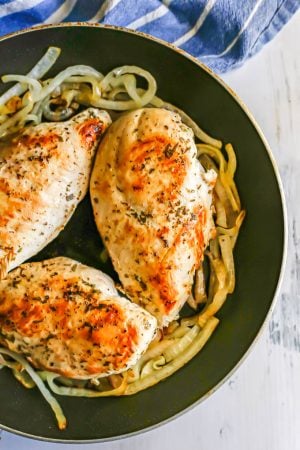 Seared chicken breasts in a large skillet with onions