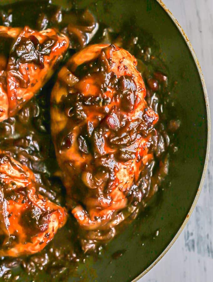 Close up of chicken breasts coated in a cranberry balsamic sauce in a large skillet