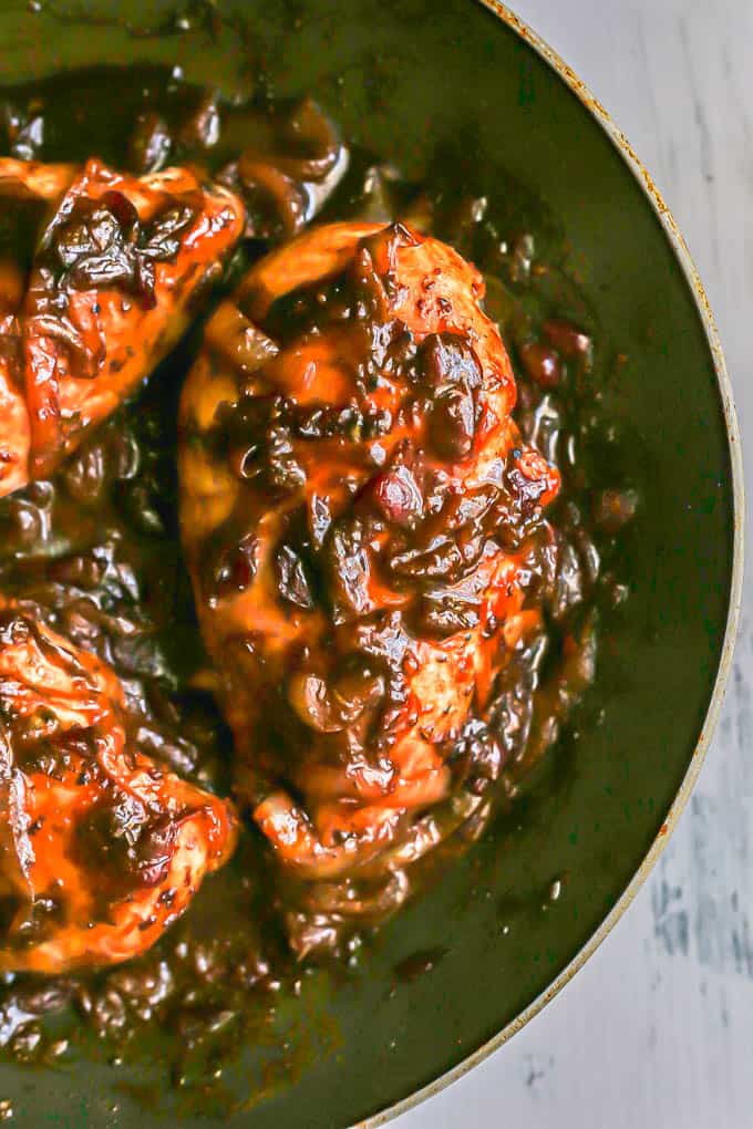 Close up of chicken breasts coated in a cranberry balsamic sauce in a large skillet