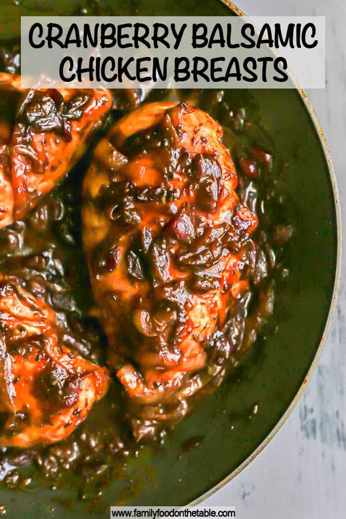 Close up of chicken breasts coated in a cranberry balsamic sauce in a large skillet with a text overlay on the photo