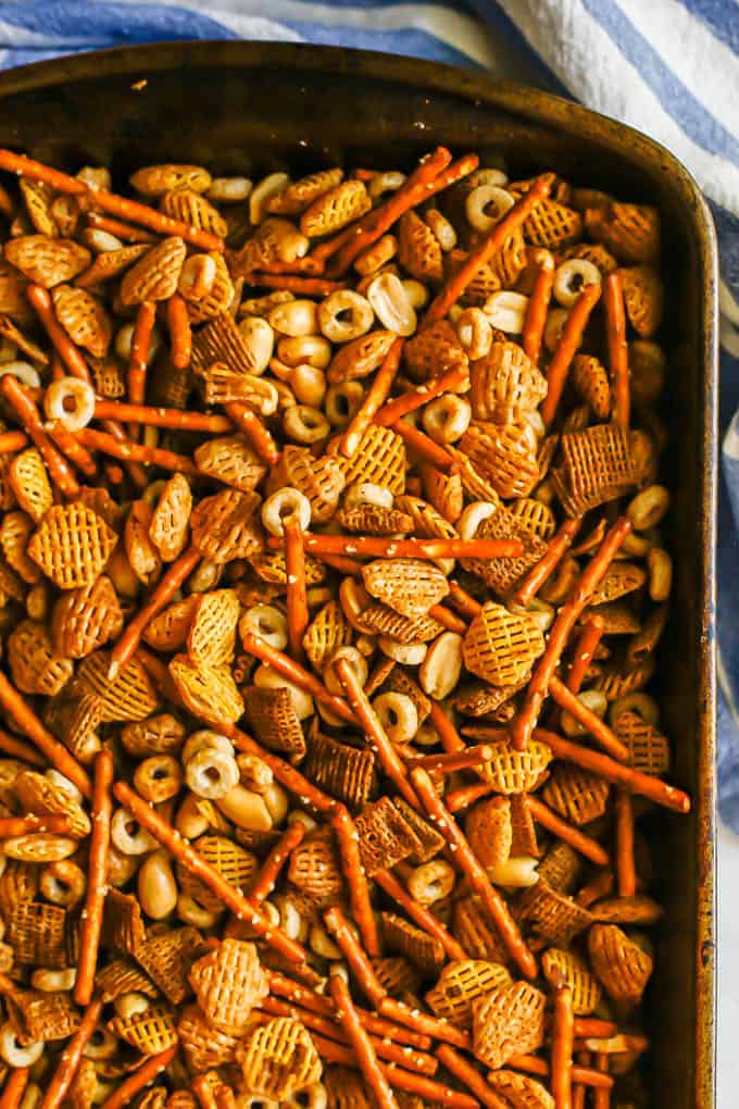 Close up of a baking pan full of homemade Chex mix with Chex, pretzels, peanuts and Cheerios