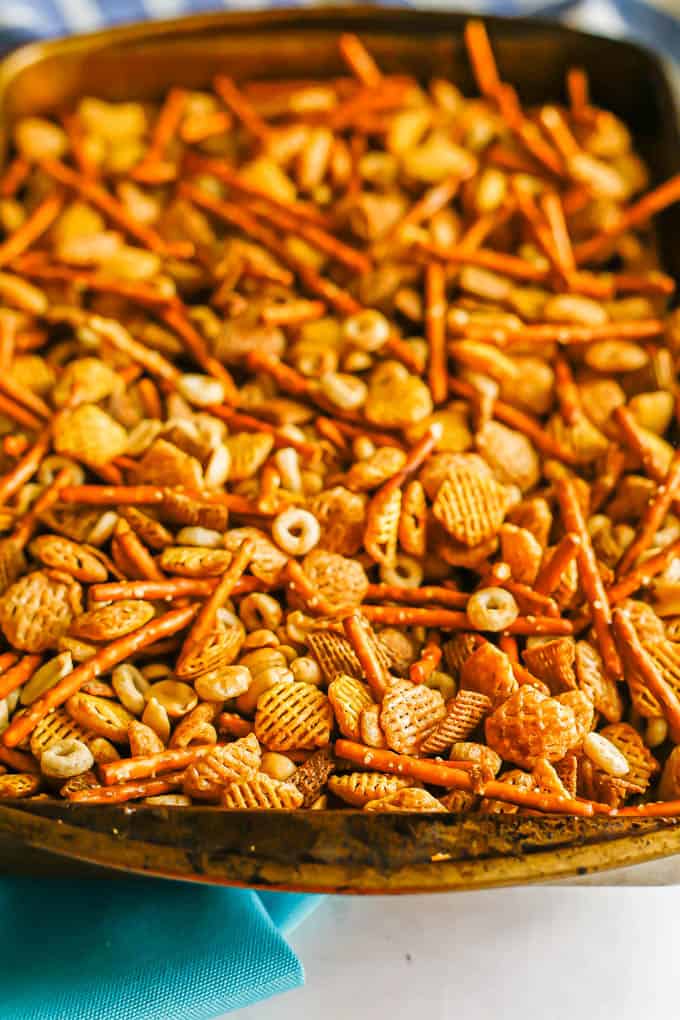 A baking pan full of homemade Chex mix with Chex, pretzels, peanuts and Cheerios