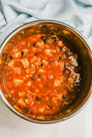 Cooked chicken chili in an Instant Pot with a turquoise towel in the background