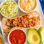 A rectangular white plate with a soft shell taco with rice and leftover turkey with bowls of toppings on the side and a text overlay on the photo