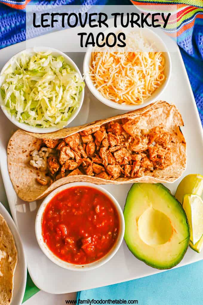 A rectangular white plate with a soft shell taco with rice and leftover turkey with bowls of toppings on the side and a text overlay on the photo