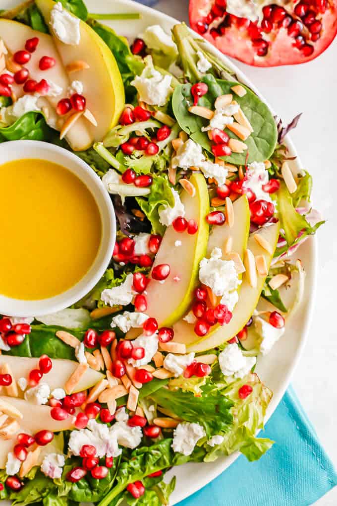 Close up of a Christmas wreath salad with mixed greens and winter fruit on a white platter