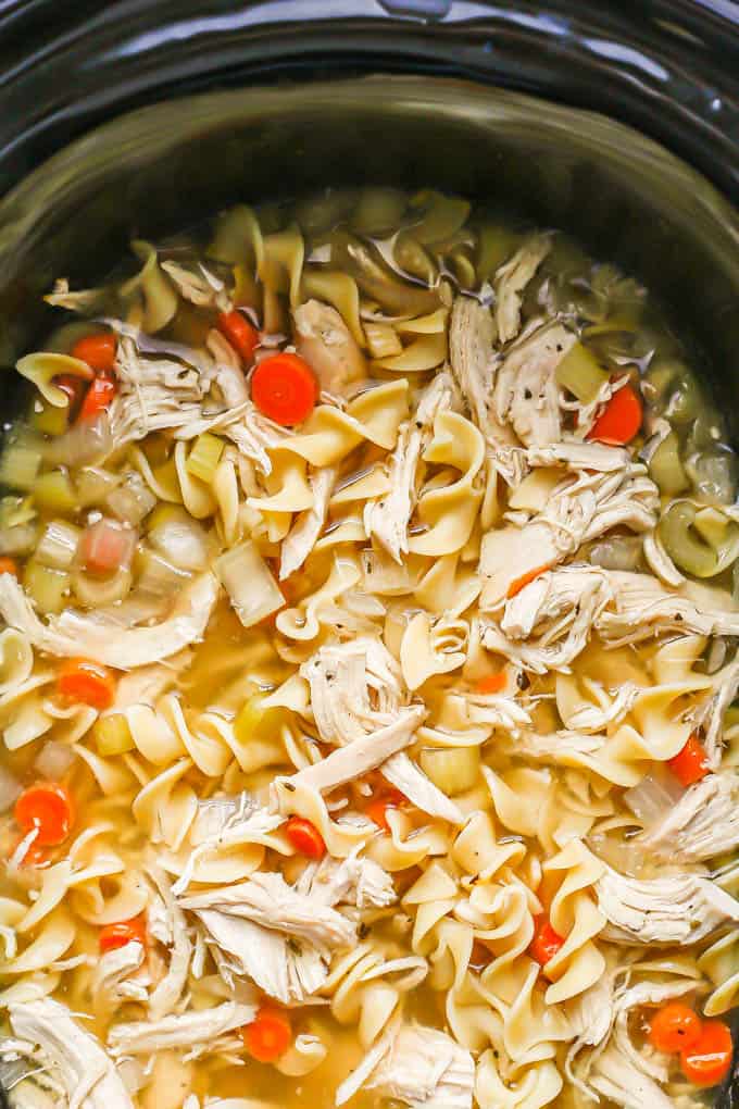 Close up of chicken noodle soup with carrots in a slow cooker