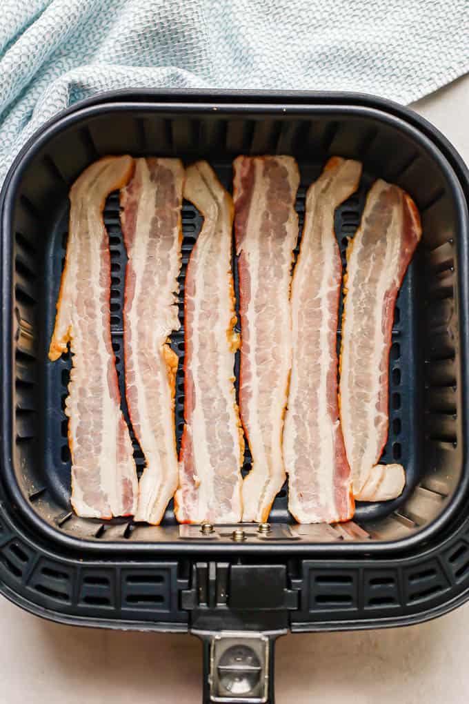 Six strips of bacon laid in an Air Fryer tray before being cooked