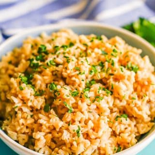 Brown rice pilaf served in a large white bowl with parsley on top
