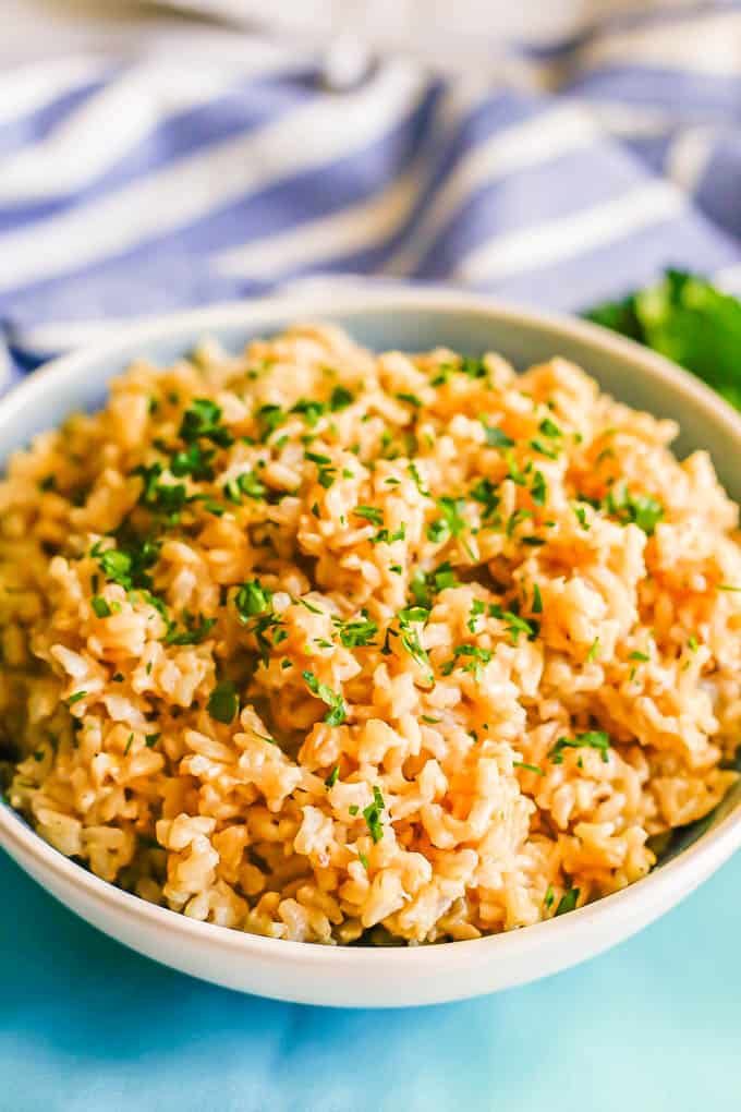 Brown rice pilaf served in a large white bowl with parsley on top