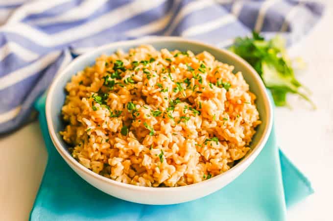 Brown rice pilaf sprinkled with fresh parsley and served in a blue and white bowl