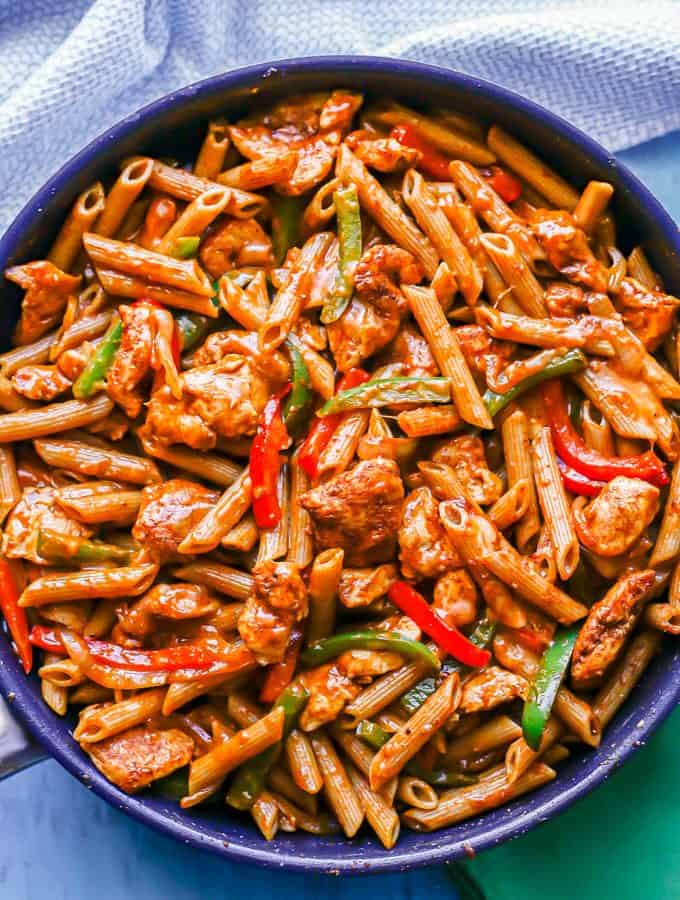 A large skillet of fajita chicken pasta with peppers and onions