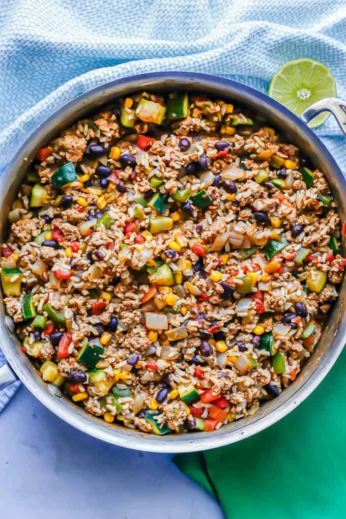 A large deep skillet with a ground turkey, rice and veggie mixture with tomatoes and beans