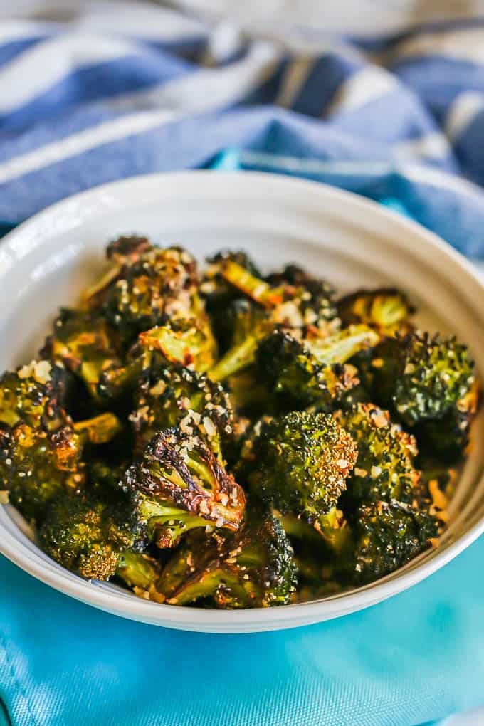 Roasted broccoli served in a white bowl on turquoise napkins