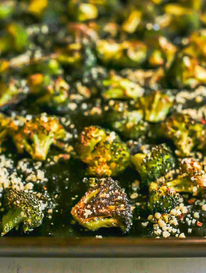 Close up of browned and roasted broccoli on a sheet pan with Parmesan on top