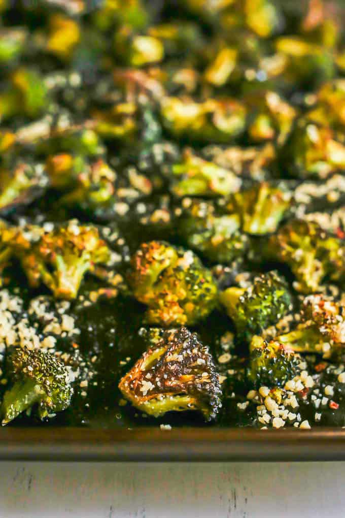 Close up of browned and roasted broccoli on a sheet pan with Parmesan on top