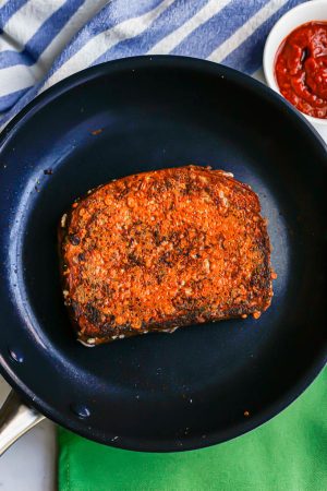 A browned grilled cheese sandwich cooking in a dark pan
