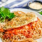 Pizza stuffed chicken breasts with marinara and melty mozzarella cheese on a bed of spaghetti with a text overlay on the photo