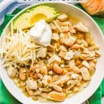 A low white serving bowl with a white chicken chili with beans and a text overlay on the image