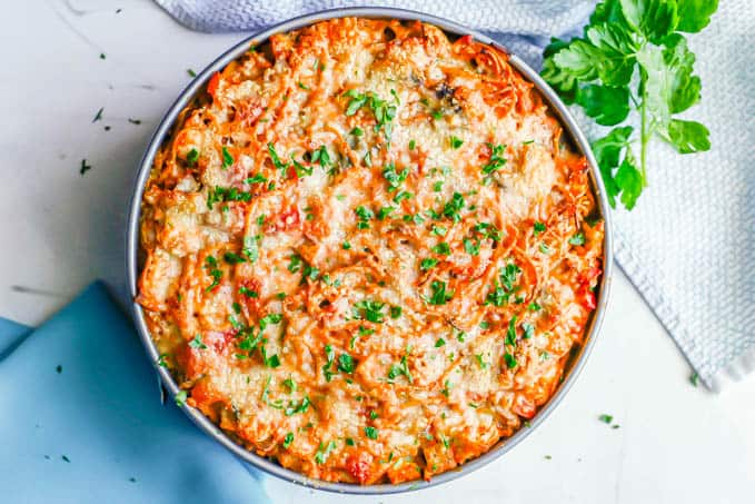 A baked spaghetti pie topped with Parmesan cheese and chopped fresh parsley