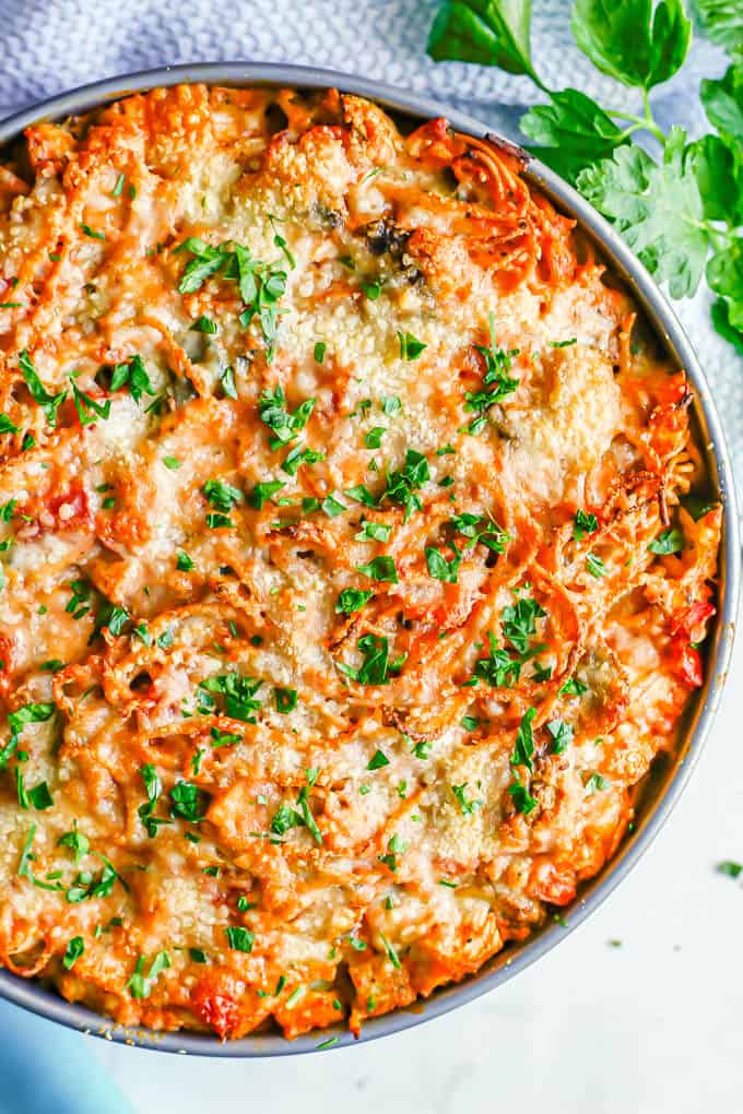 Close up of a chicken and veggie spaghetti pie in a springform pan with parsley sprinkled on top