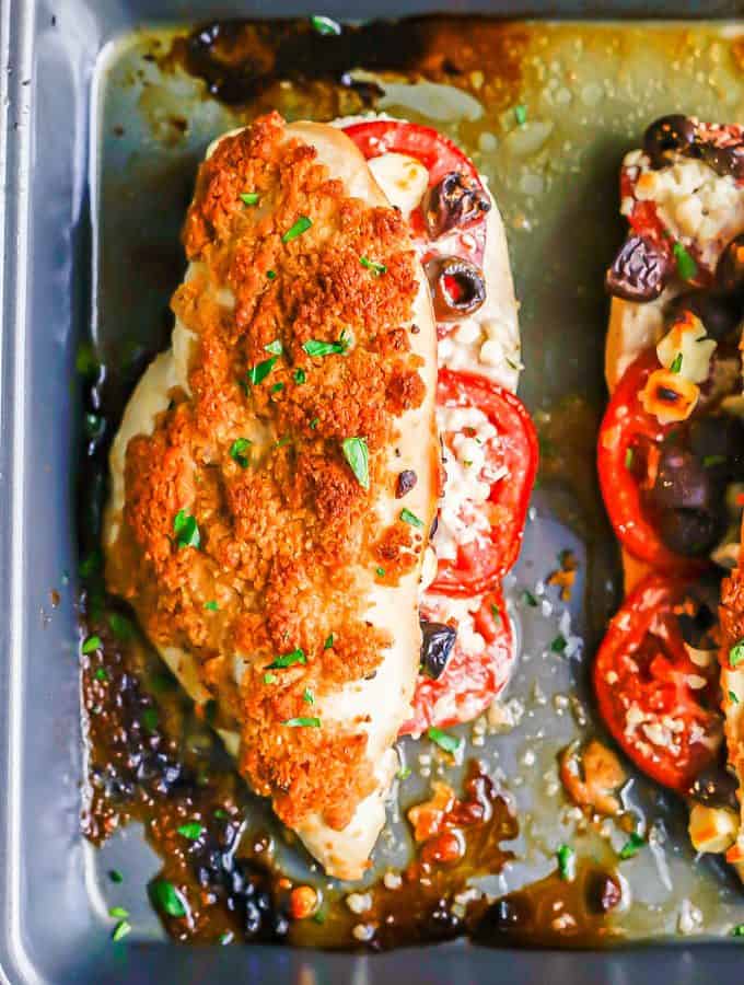 A baked stuffed chicken breast with tomatoes, olives and feta and a breadcrumb topping