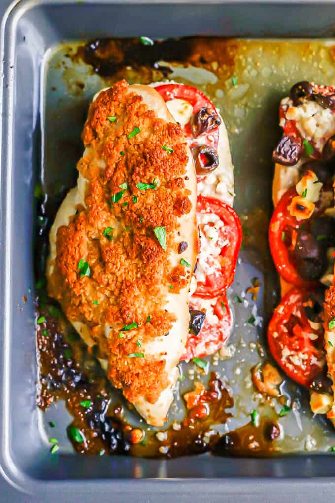 A baked stuffed chicken breast with tomatoes, olives and feta and a breadcrumb topping