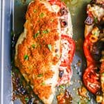 A baked stuffed chicken breast with tomatoes, olives and feta and a breadcrumb topping and a text overlay on the photo