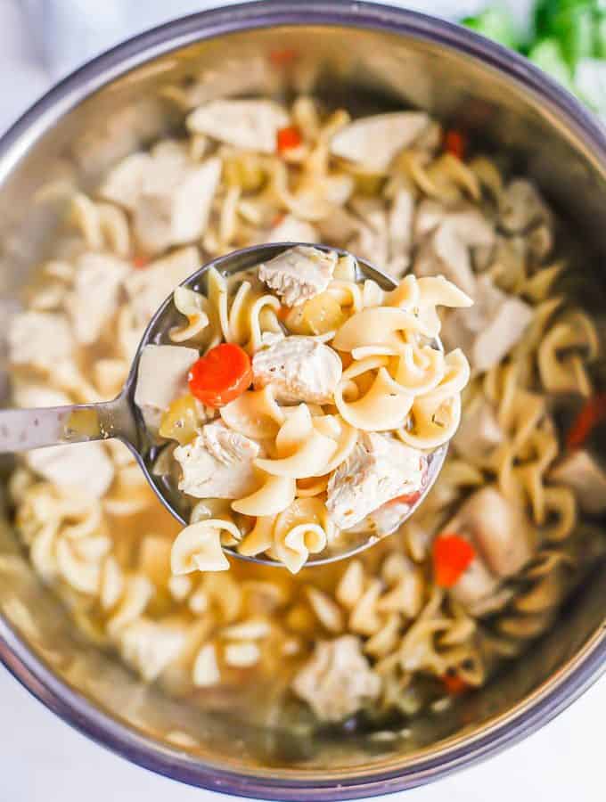 A ladle full of chicken noodle soup being lifted from an Instant Pot insert