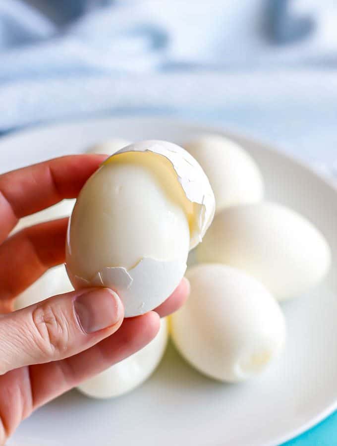 A hand holding a hard boiled egg with the shell being removed