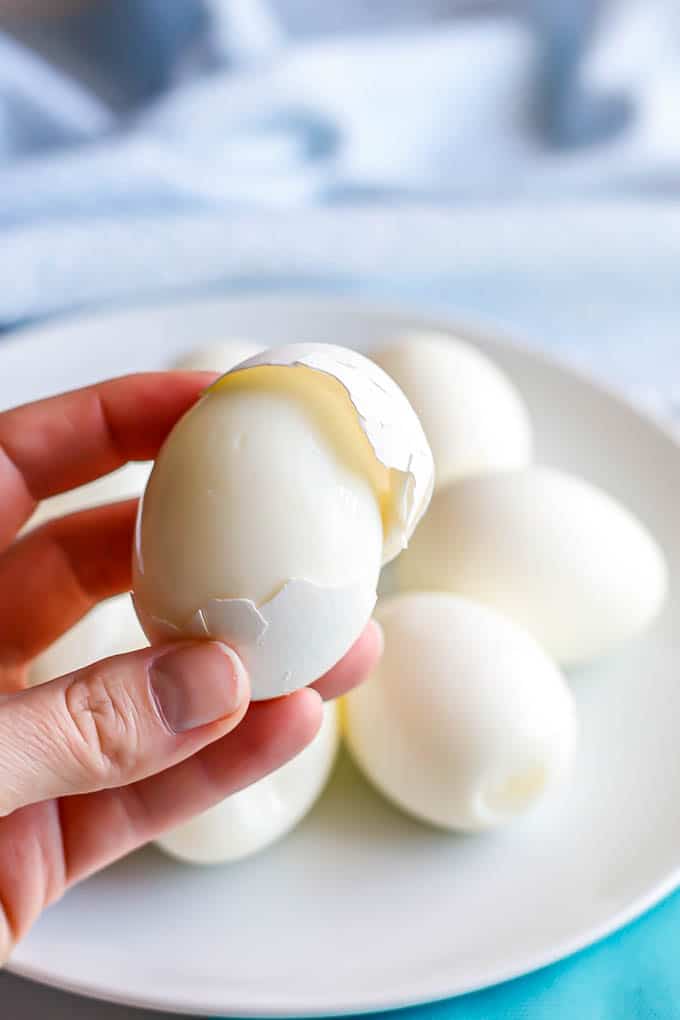 A hand holding a hard boiled egg with the shell being removed