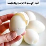 A hand holding a hard boiled egg with the shell being removed and a text overlay on the photo