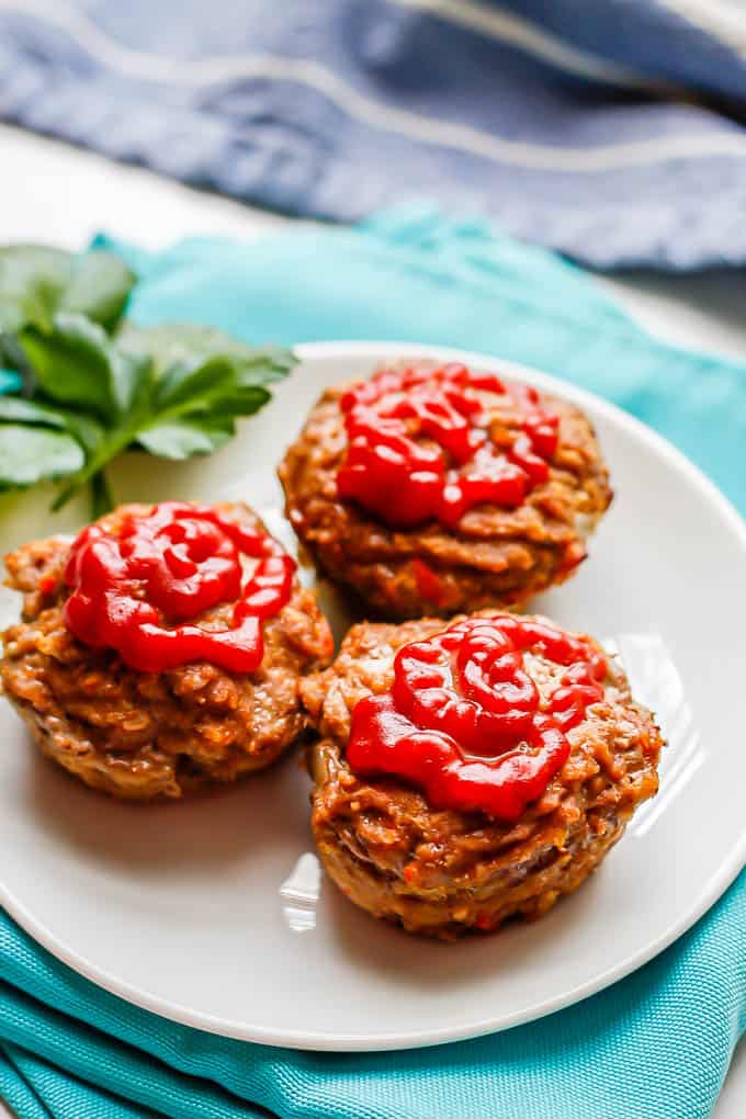 A small white plate with 3 mini meatloaf muffins topped with ketchup