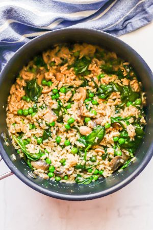 Brown rice with peas, spinach and mushrooms in a large dark pot after cooking