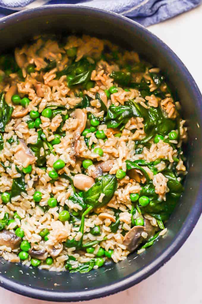 A dark pot with a mixture of brown rice and vegetables after being cooked