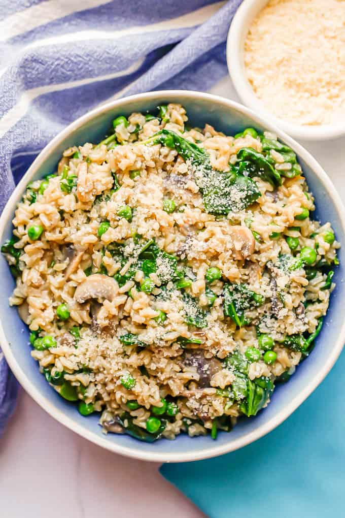 A mix of brown rice and veggies with Parmesan cheese served in a blue and white bowl