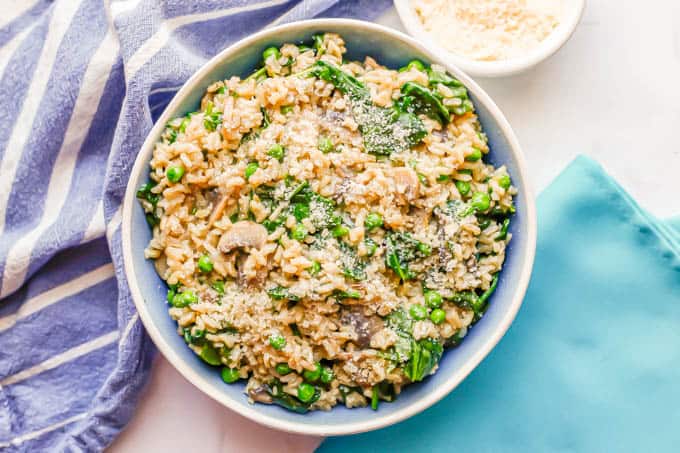 Brown rice and veggies mixed together and served with Parmesan cheese in a blue and white bowl