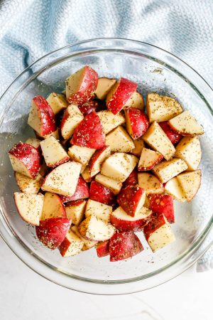 Cubed red potato pieces in a large bowl and seasoned with olive oil and seasonings