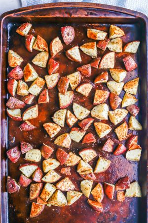 A sheet pan with cubed seasoned potatoes after being roasted