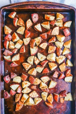 A sheet pan with cubed seasoned potatoes after being roasted