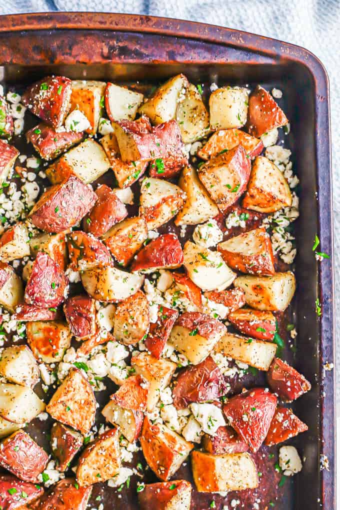 A sheet pan with cubed and roasted red potatoes mixed with parsley and feta cheese