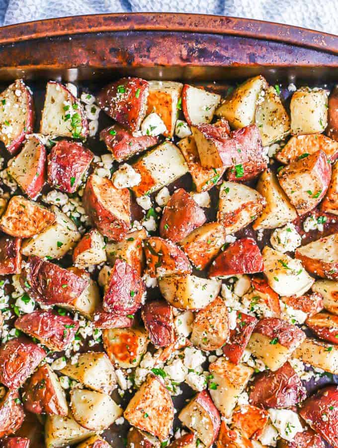 A sheet pan with roasted red potatoes mixed with feta cheese and fresh herbs