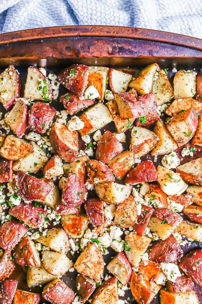 A sheet pan with roasted red potatoes mixed with feta cheese and fresh herbs