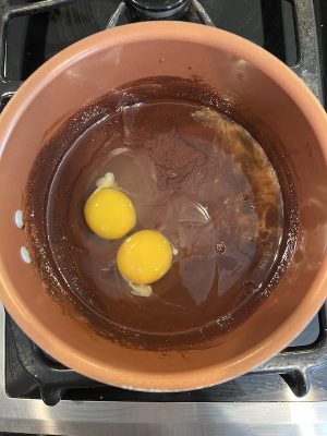Eggs added to a chocolate mixture in a copper pot on the stove