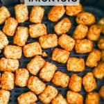 Crispy golden brown tater tots in an Air Fryer tray after cooking with a text overlay on the photo