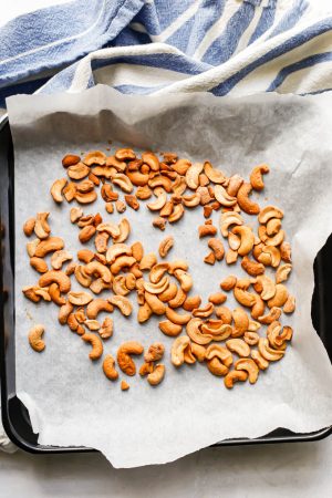 Toasted cashew pieces on a parchment paper lined baking tray