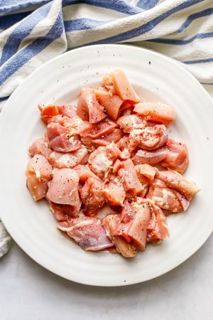 Seasoned cut pieces of chicken thighs in a white bowl