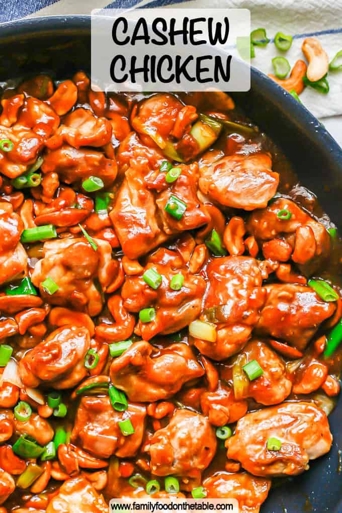 Saucy cashew chicken in a large skillet with green onions on top and a text overlay on the photo