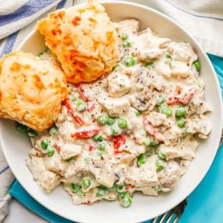 Chicken a la King served with two cheesy biscuits in a low white bowl with a fork to the side